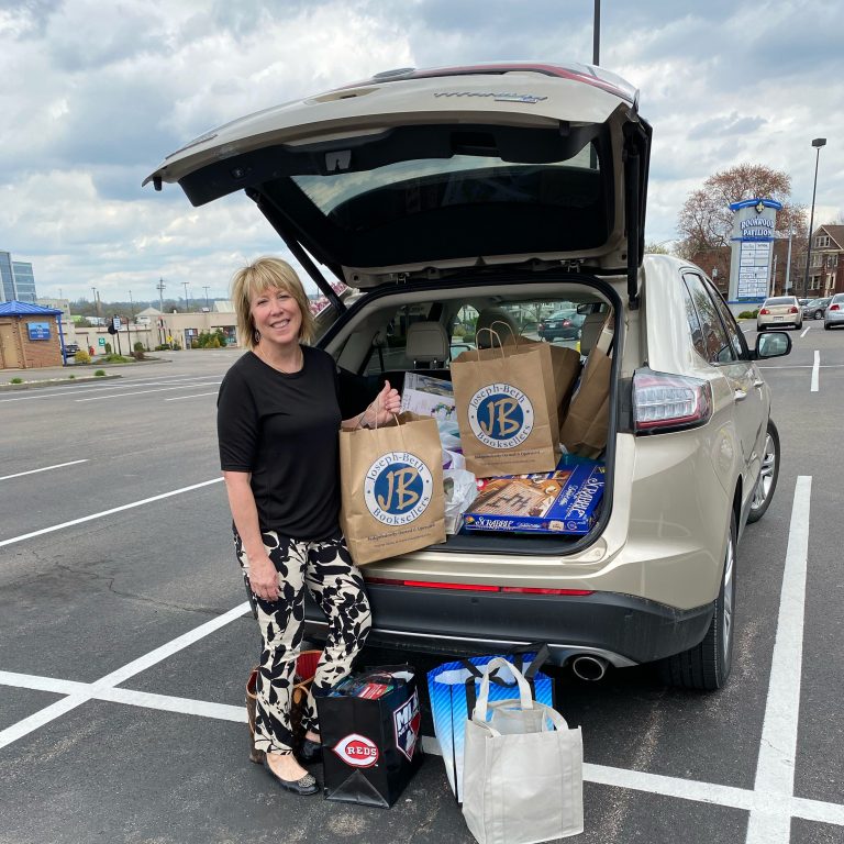 Photo of Kim Vincent standing beside her car full of Joseph-Beth Booksellers shopping bags.