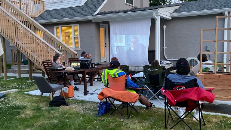 Photo of individuals watching movie outside.