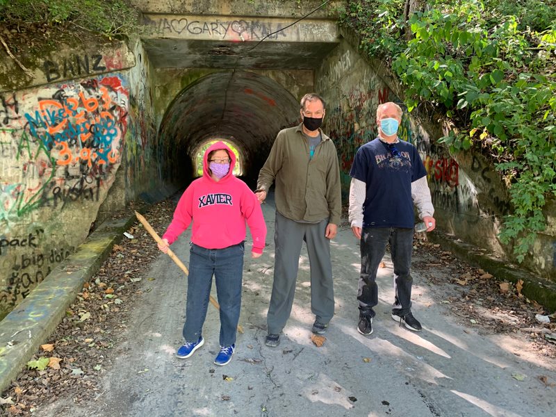 Photo of three people standing on a path outside.