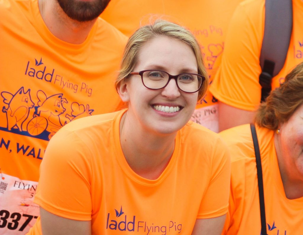 Photo of Hannah Eldridge smiling at camera, wearing an orange shirt.