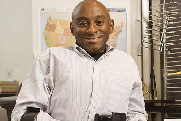 Photo of man sitting and smiling at camera.